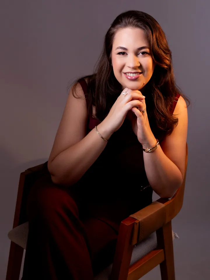 Rebeca Marinho sentada, com um livro, em retrato profissional